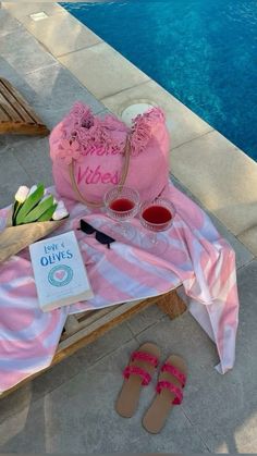 a pink bag and some sandals near a pool