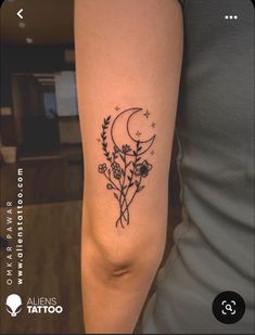 a woman's arm with a tattoo on it that has flowers and the moon