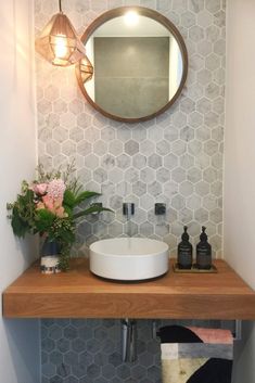 a bathroom with a sink, mirror and flowers on the counter top in front of it