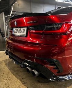 the rear end of a red bmw car in a garage with no one around it