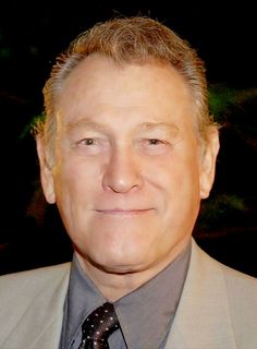 a man in a suit and tie smiling at the camera with his eyes wide open