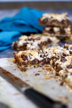 chocolate and coconut bars sitting on top of a cutting board next to a blue napkin