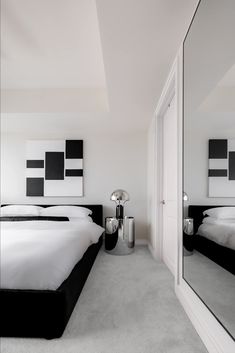 a large white bed sitting next to a tall mirror