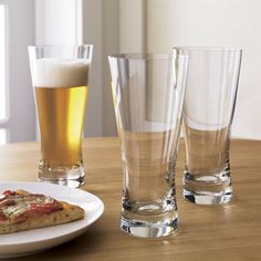 there are three glasses on the table and one is half eaten pizza in front of it