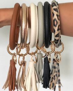 a woman's arm with several different bracelets and tassels on it