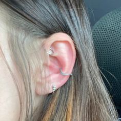 a person with ear piercings on their ears and in the back seat of a car