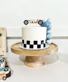 a white cake sitting on top of a wooden stand next to cookies and other items