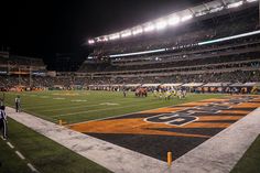 a football game is being played on an empty field at night with the lights on