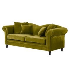 a green velvet couch with pillows on it's arms and back rests against a white background