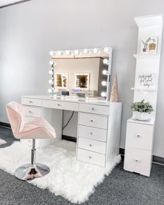 a white vanity with lights on it and a pink chair