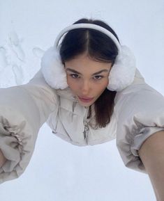 a woman with headphones on her ears is posing for the camera in the snow