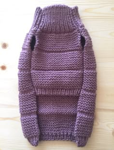 a purple sweater sitting on top of a wooden floor