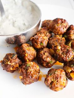 a white plate topped with meatballs next to a bowl of yogurt