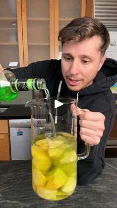 a man is pouring water into a blender filled with fruit