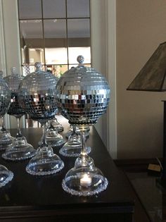 several disco ball glasses on a table in front of a mirror and lampshade