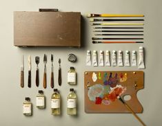 an assortment of art supplies including paint, brushes and acrylic paints on a table