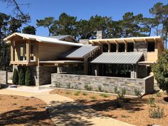 a large house with stone walls and metal roofing on the front porch, surrounded by trees