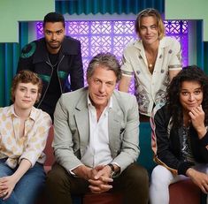 the cast of modern family sitting on a couch in front of a colorful wall and blue curtains