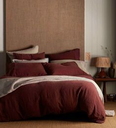 the bed is made up with red linens and pillows on it, along with a brown headboard