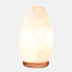 a white himalayan salt lamp sitting on top of a wooden base