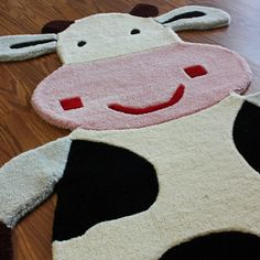 a cow rug is laying on the floor next to a wooden floor with an animal shaped rug