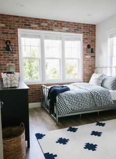 a bedroom with brick walls and white bedding in the corner, along with an area rug on the floor