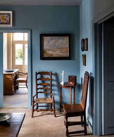 a room with blue walls and two wooden chairs