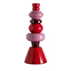 a red and pink vase sitting on top of a white table