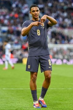 a man standing on top of a soccer field holding his hand out to the side