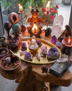 an assortment of crystals and candles on a table in front of a window with a lit candle