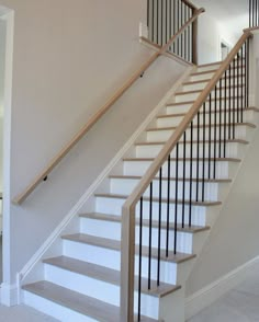 there is a white stair case in the house with wood handrails and black rails