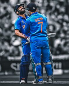 two men standing next to each other in front of a crowd wearing blue uniforms and holding bats