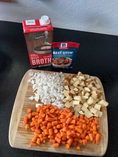 chopped up vegetables on a cutting board next to a carton of broth