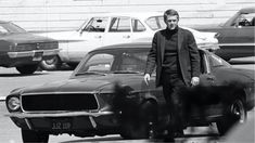 a man standing next to a car in a parking lot