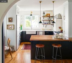 an archway leads into a kitchen with two stools in the foreground and open shelves on the far wall