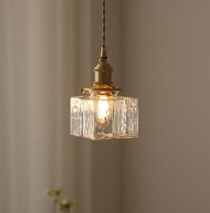 a light hanging from a ceiling in a room with flowers on the table next to it