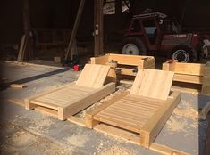 two wooden lounge chairs sitting next to each other on top of a cement floor in front of a tractor