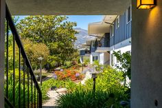 the view from inside an apartment building looking out onto a garden and mountains in the distance