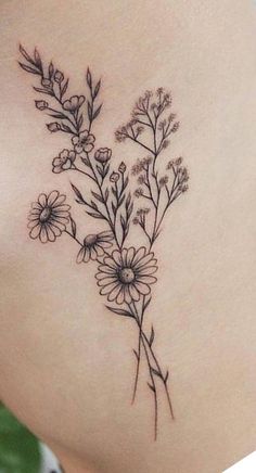 a woman's stomach with flowers on it and leaves in the back tattoo design