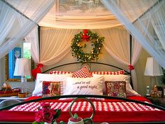 a bed with red and white bedspread sitting under a christmas wreath on top of it