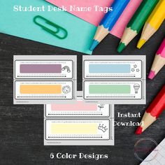 four color pencils and three different name tags on top of a black table with colored paper