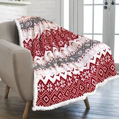 a red and white blanket sitting on top of a chair in front of a fireplace