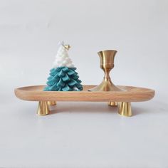 a small christmas tree on a wooden tray with two candles in the shape of a pine cone