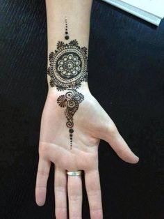 a woman's hand with a henna tattoo on it, and an intricate design