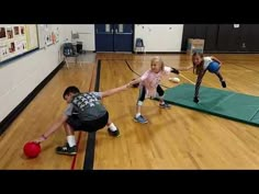 three children are playing with balls in an indoor gym while one child is reaching for the ball