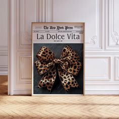 a poster with a leopard print bow hanging on the wall next to a wooden floor