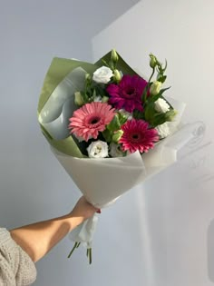 a woman holding a bouquet of flowers in her hand with white and pink blooms on it