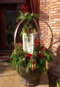 a lantern is decorated with greenery and red ornaments on the outside of a house