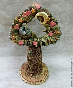 a decorative tree with two birds and hearts on it's base, sitting on a white surface