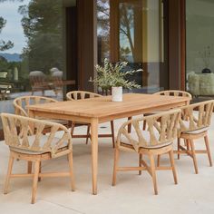 a wooden table with six chairs and a potted plant sitting on top of it